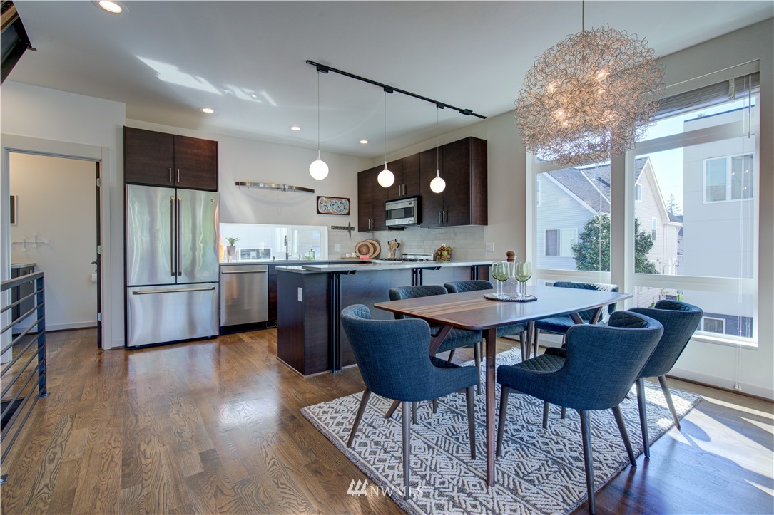 4262 Linden Avenue North Seattle, WA 98103 - Photo 26 of 40 a kitchen with stainless steel appliances a dining table chairs and wooden floor