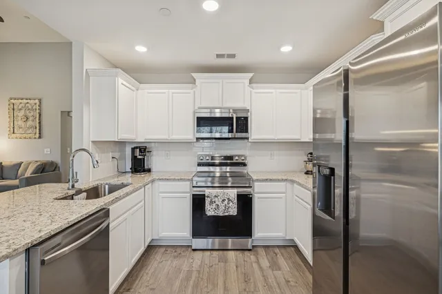 a kitchen with stainless steel appliances granite countertop a refrigerator a sink a stove a microwave and island