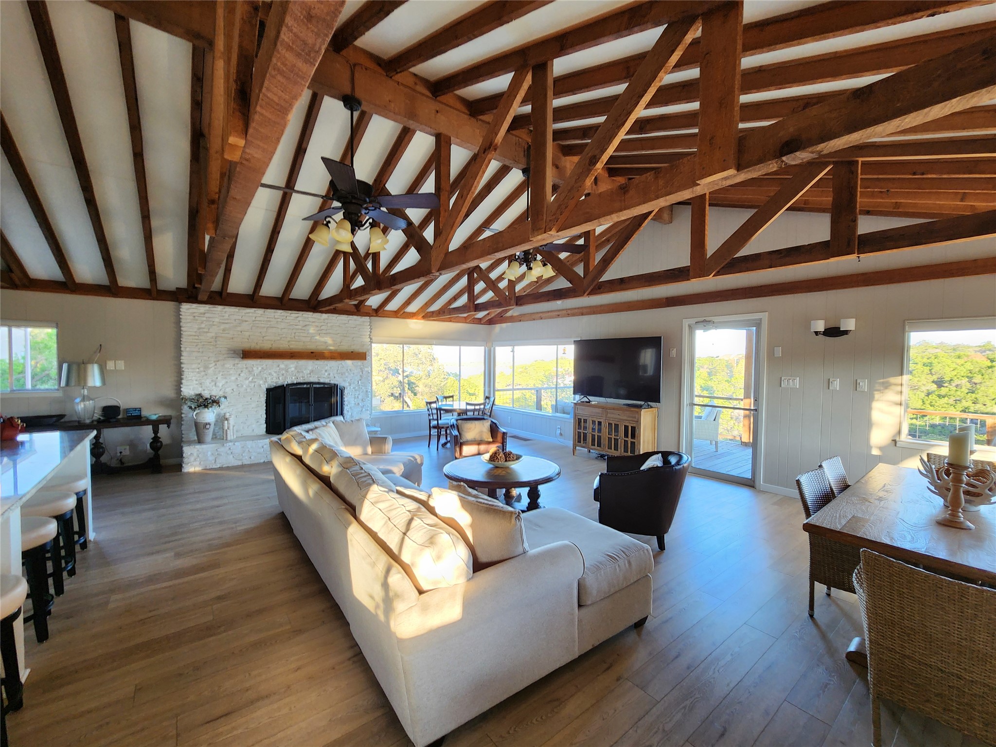 3807 Boat Dock Road Lago Vista, TX 78645 - Photo 6 of 37 A spacious living area boasts exposed timber beams and a charming fireplace, opening to a deck with serene views.