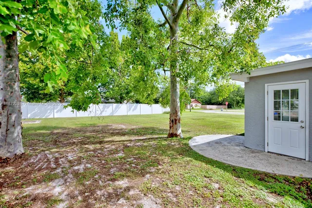 a view of a house with a yard and a large tree