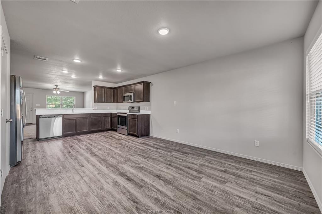 1629 Lucky Street Bryan, TX 77807 - Photo 7 of 11 a large white kitchen with wooden floors and a fireplace