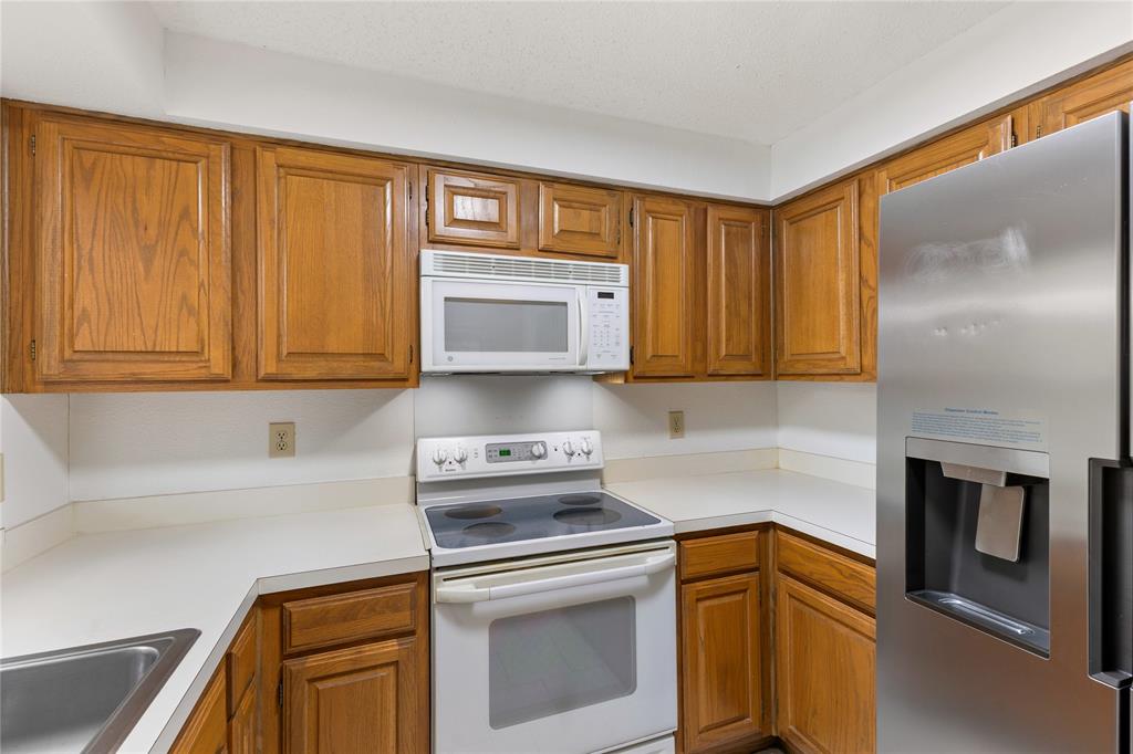 5859 Frankford Road, Unit 812 Dallas, TX 75252 - Photo 14 of 29 a kitchen with stainless steel appliances granite countertop a sink a stove and a microwave oven with granite countertops