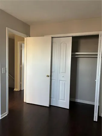 a view of an empty room with wooden floor & closet