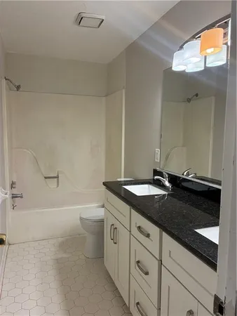 a bathroom with a granite countertop sink a toilet and bathtub