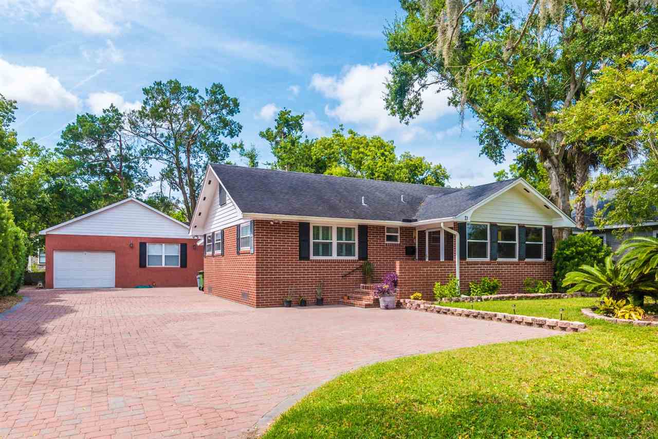 a front view of a house with a yard and potted plants