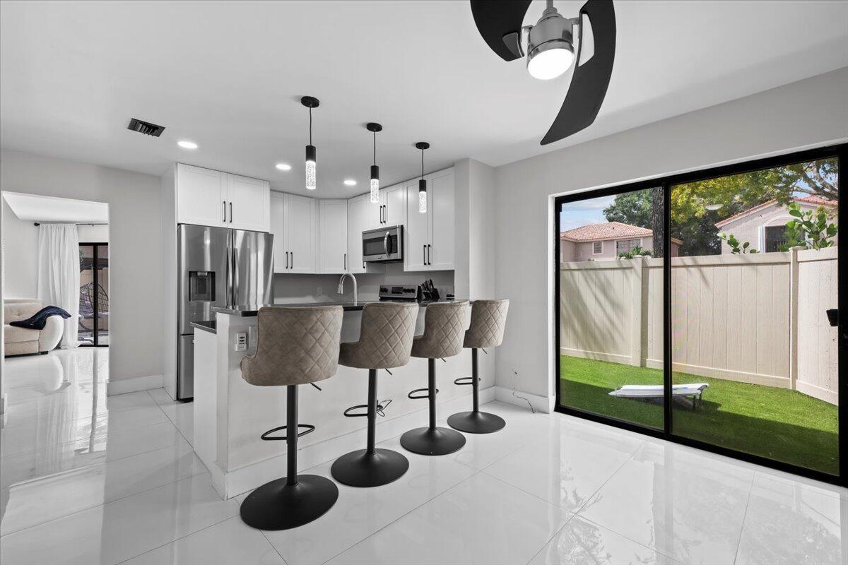 1779 Harborside Circle Wellington, FL 33414 - Photo 8 of 23 a kitchen with stainless steel appliances kitchen island granite countertop a refrigerator a oven a sink with a dining table and chairs