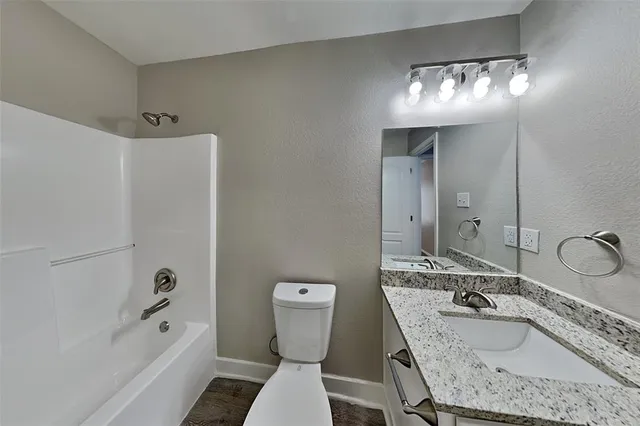 a bathroom with a granite countertop sink a toilet a mirror and shower