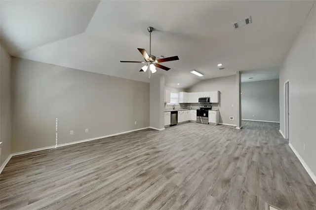 a view of a livingroom with a kitchen stove and wooden floor