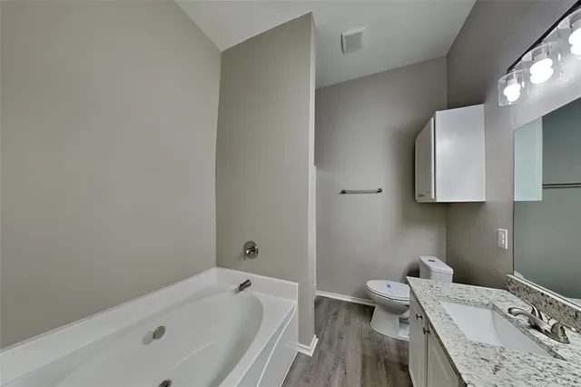 a bathroom with a granite countertop sink a toilet and bathtub