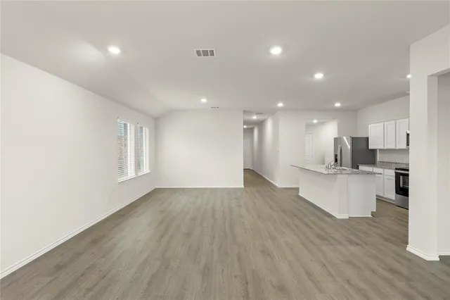 a view of kitchen with kitchen island wooden floors wooden cabinets and living room