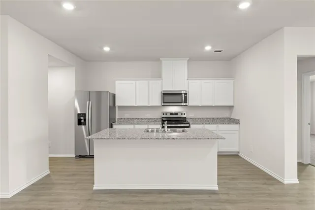 a kitchen with stainless steel appliances granite countertop a refrigerator a stove and a wooden floors