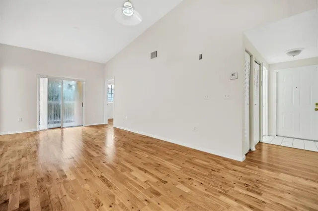 a view of an empty room with wooden floor and a window