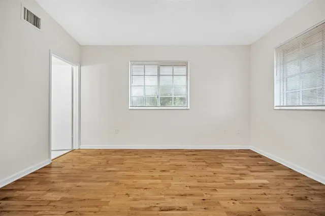 an empty room with wooden floor and windows