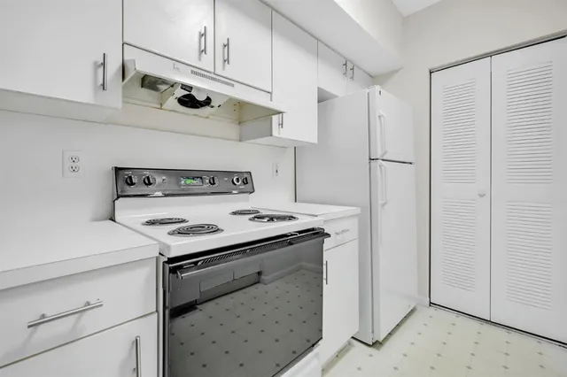 a kitchen with stainless steel appliances white cabinets and a stove top oven