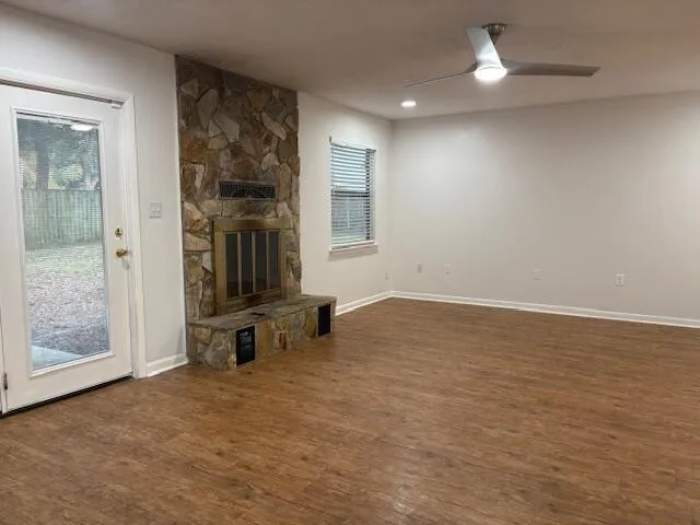 an empty room with wooden floor and a ceiling fan