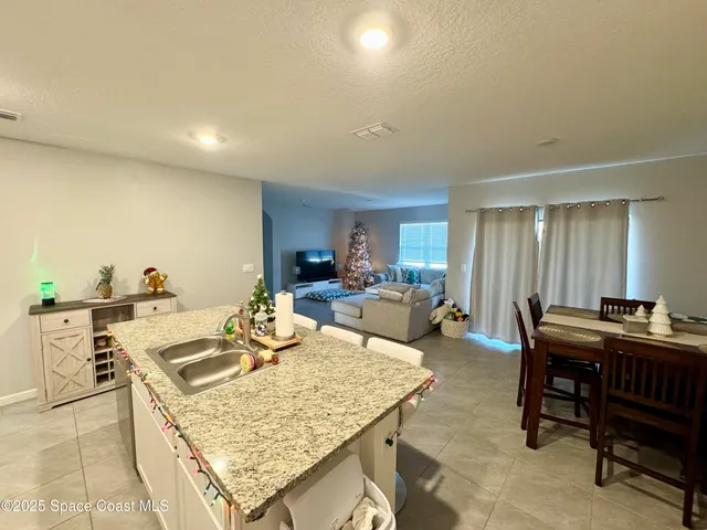 a living room with furniture a rug and kitchen view