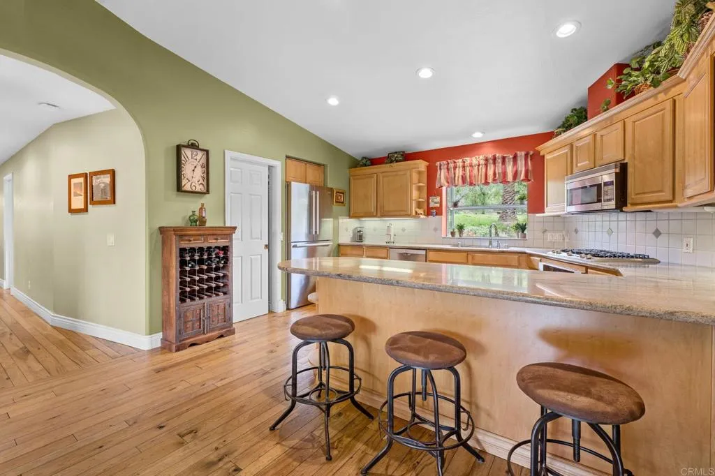 31619 Vía Puerta Del Sol Bonsall, CA 92003 - Photo 41 of 70 a kitchen with stainless steel appliances granite countertop a table chairs and a refrigerator