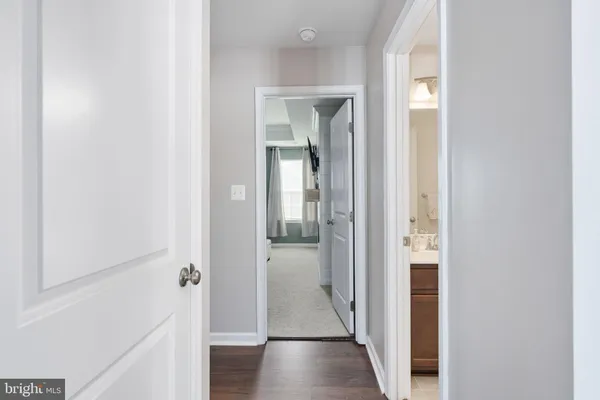 a view of a hallway with wooden floor and a bathroom