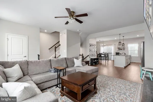 a living room with furniture kitchen view and a ceiling fan