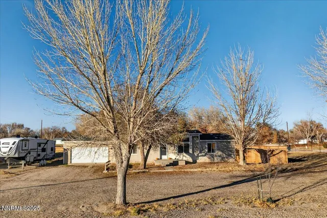 a front view of a house with a yard covered with snow and trees