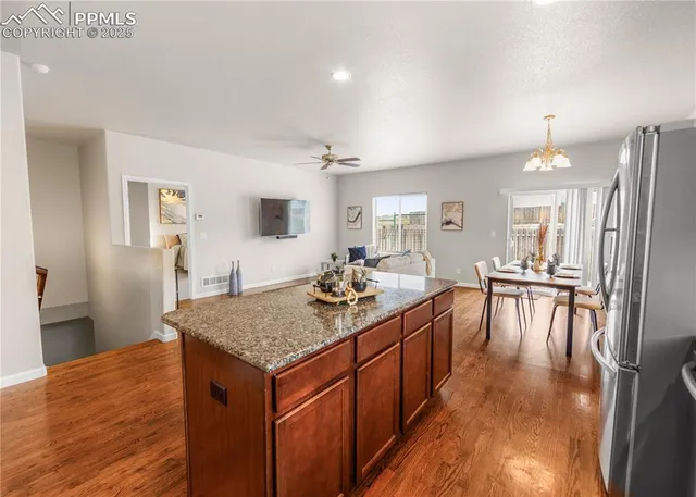 a dining hall with stainless steel appliances granite countertop a stove top oven a dining table and chairs with wooden floor