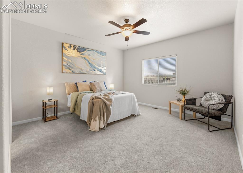 11324 Neutra Grove Peyton, CO 80831 - Photo 26 of 49 a spacious bedroom with a bed and a ceiling fan