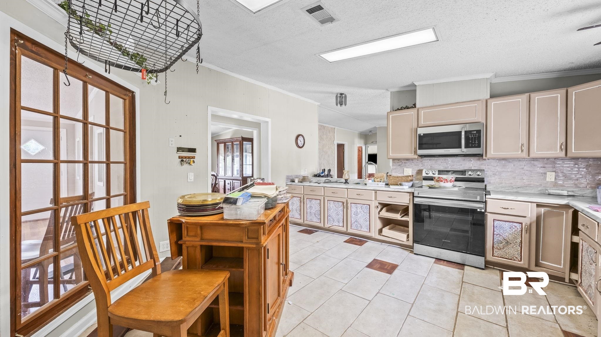 34985b Spring Road South, Unit B Stapleton, AL 36578 - Photo 18 of 31 Kitchen featuring tiled flooring, stainless steel appliances, upper and lower cabinetry, and a full-height tiled backsplash