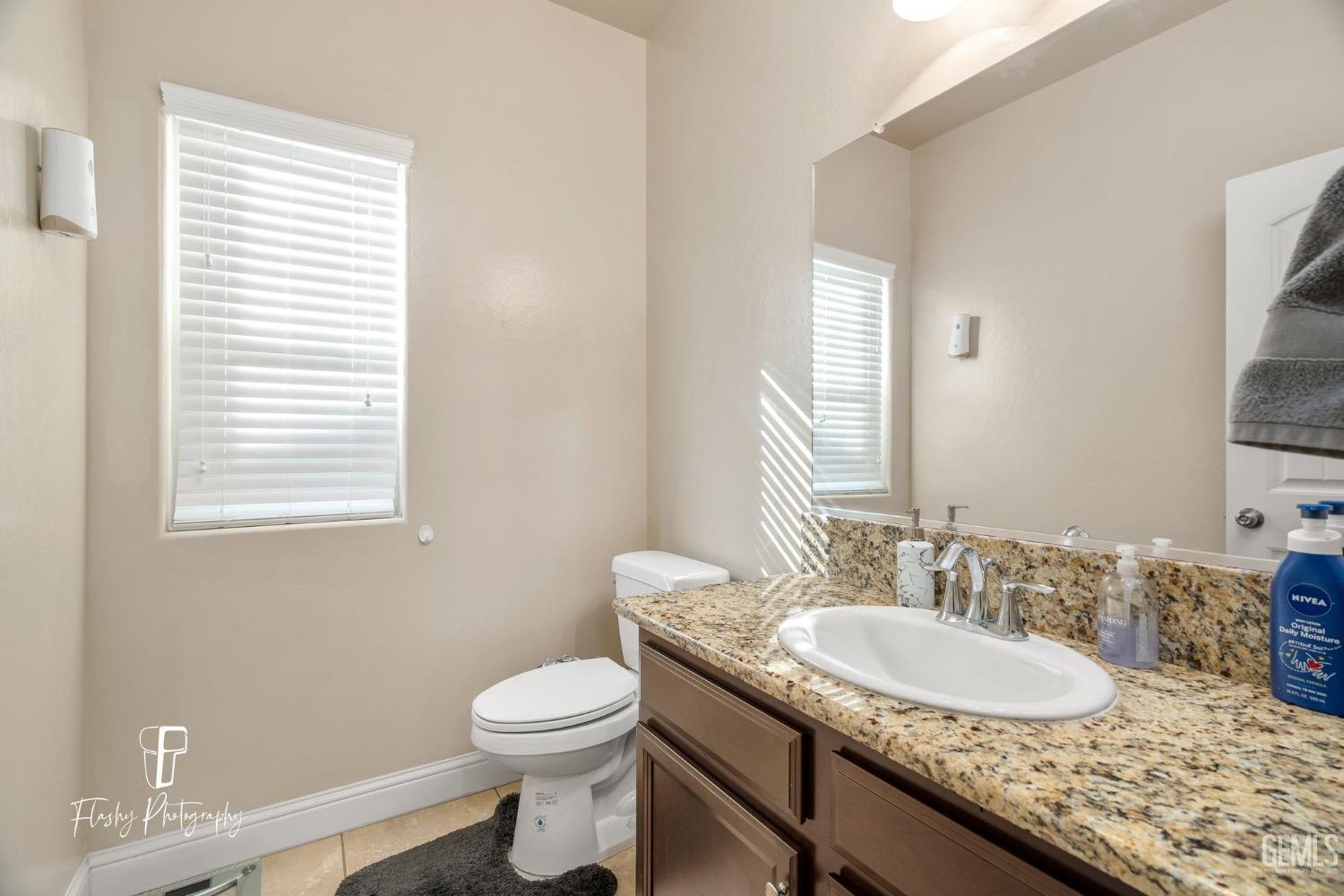 Undisclosed Address Bakersfield, CA 93313 - Photo 12 of 36 a bathroom with a granite countertop sink a toilet and a mirror
