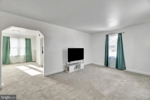 an empty room with windows and view of livingroom