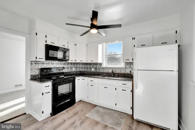 a kitchen with granite countertop a refrigerator a stove a microwave and wooden cabinets