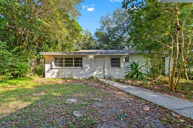 a backyard of a house with plants and large trees