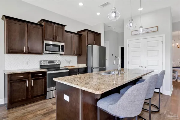 a kitchen with stainless steel appliances granite countertop a kitchen island hardwood floor sink and stove