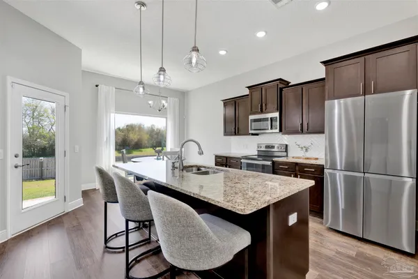 a kitchen with granite countertop a table chairs microwave and refrigerator