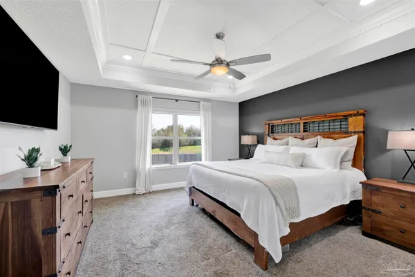 a bedroom with a bed a flat screen tv and a chandelier