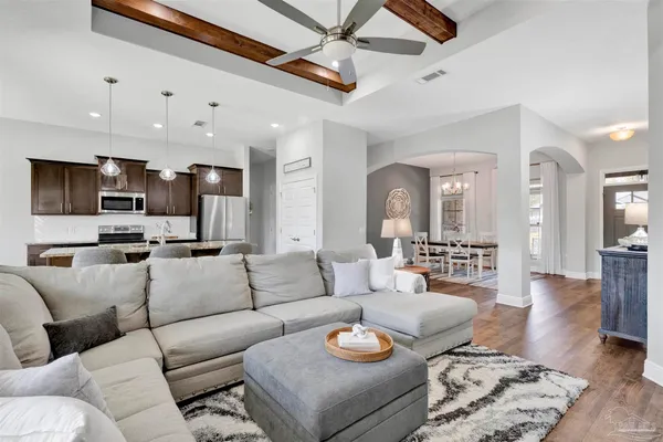 a living room with furniture kitchen view and a chandelier