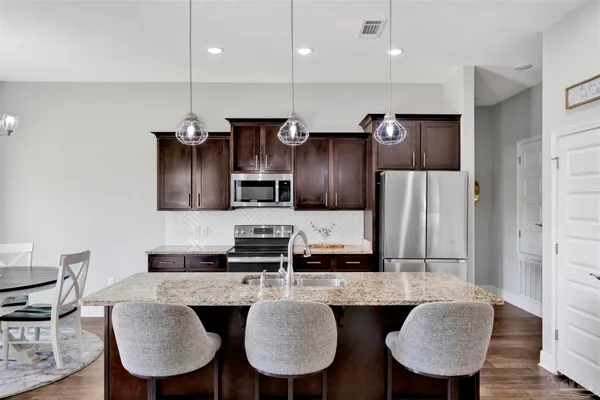 a kitchen with stainless steel appliances granite countertop a kitchen island a table and chairs in it
