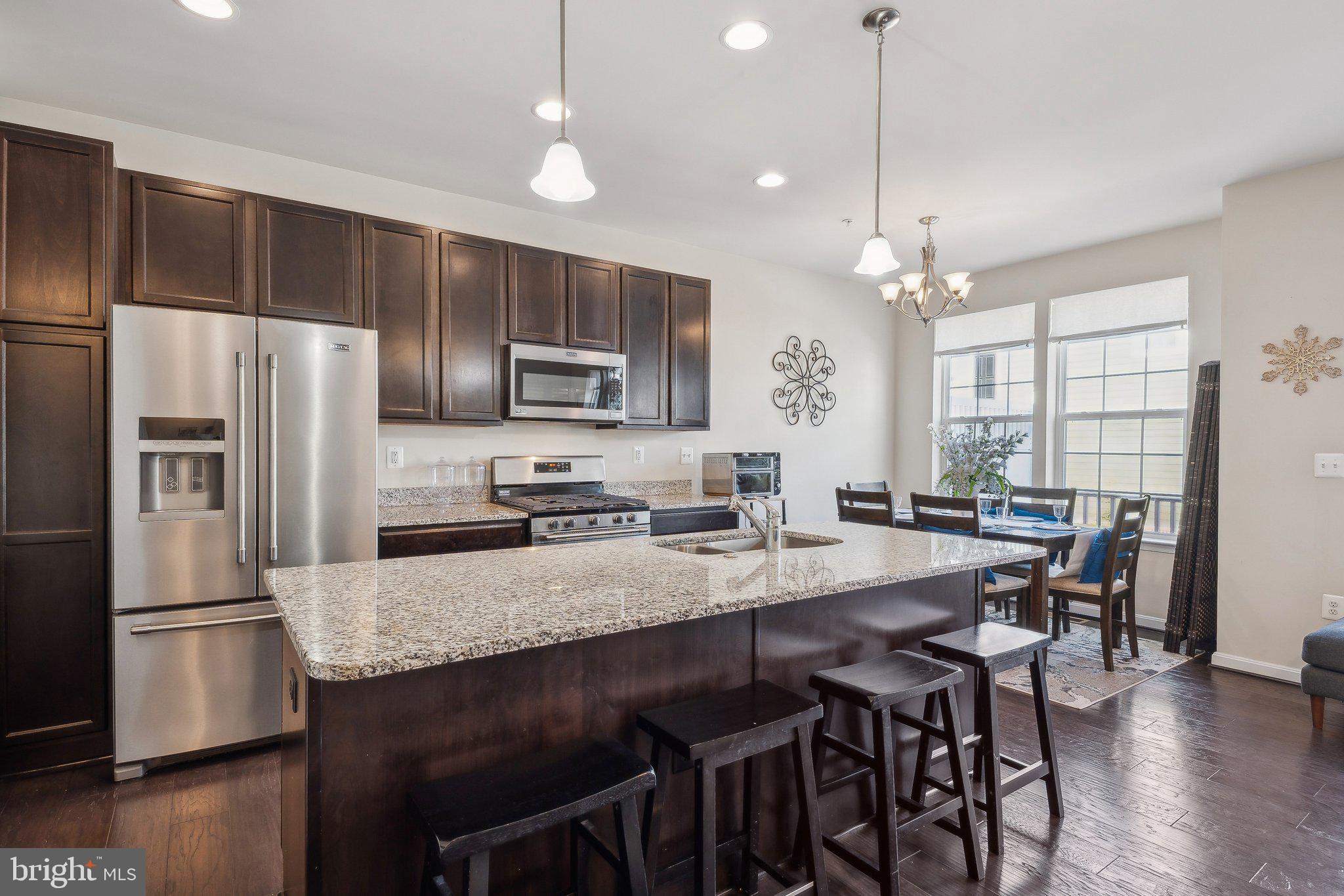 58 Mustang Drive La Plata, MD 20646 - Photo 9 of 42 a kitchen with granite countertop a refrigerator a stove a kitchen island with a dining table and wooden floor