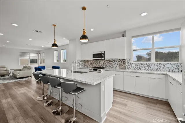 a kitchen with a sink a center island stainless steel appliances and cabinets