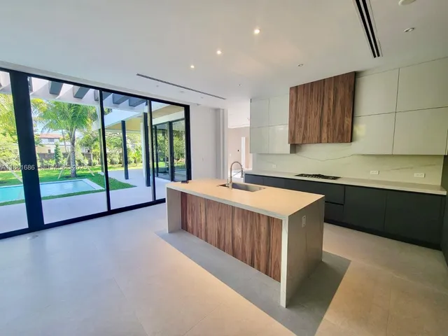 a large white kitchen with a refrigerator and a sink