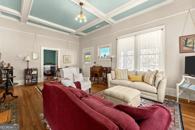 a living room with furniture large windows and wooden floor