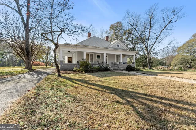 a front view of a house with a yard covered with snow and trees
