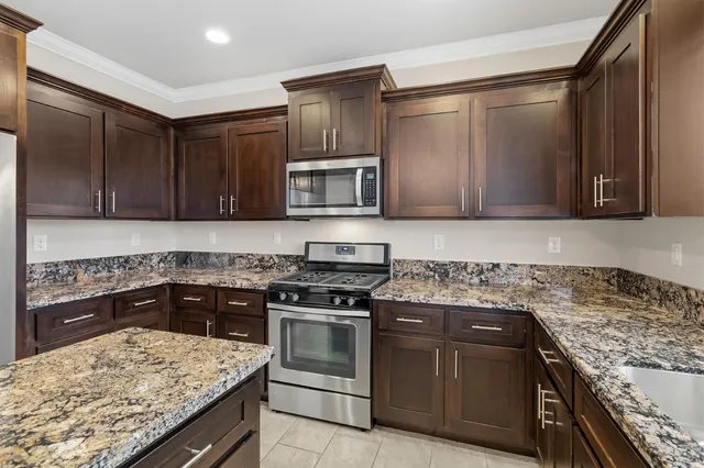 a kitchen with granite countertop cabinets stainless steel appliances and a counter space