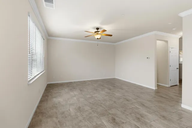 an empty room with a window and a ceiling fan