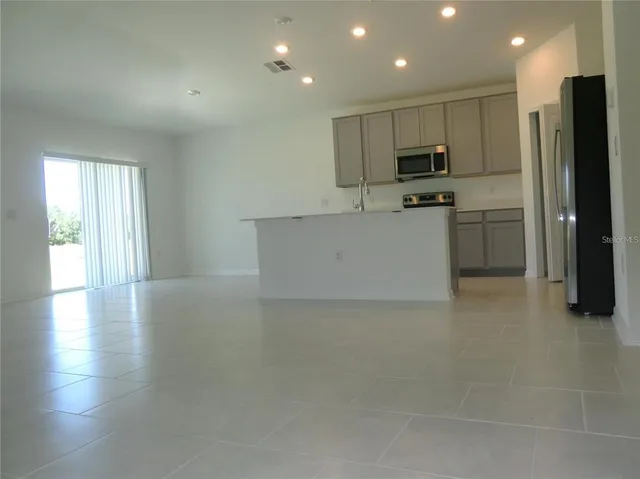 a view of kitchen with stainless steel appliances granite countertop a stove a sink a refrigerator and white cabinets with wooden floor