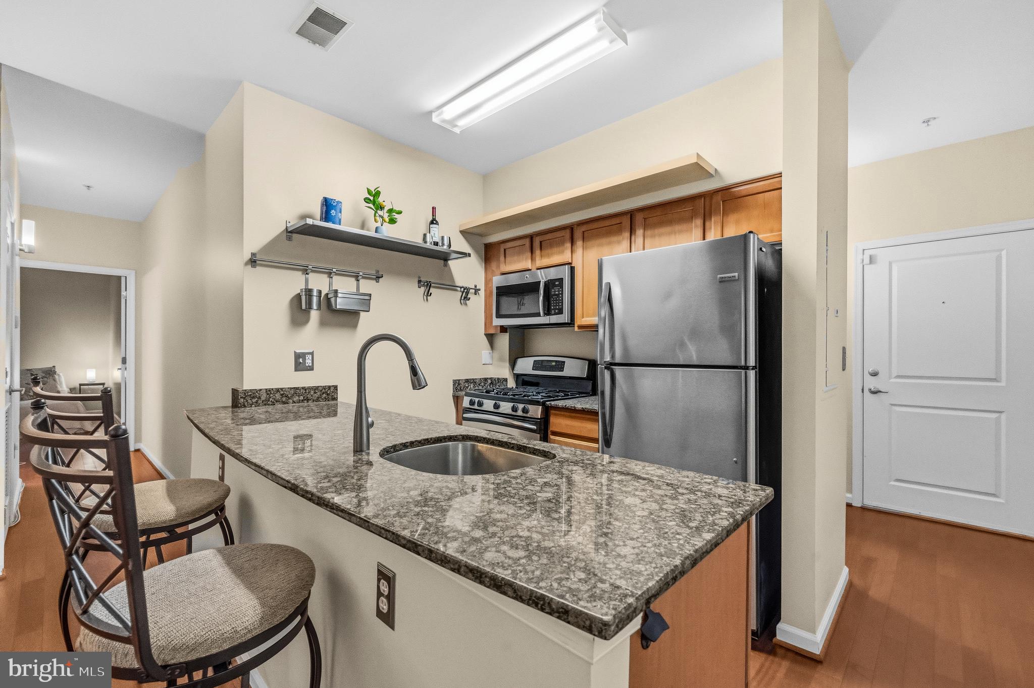 7923 Eastern Avenue Northwest, Unit 105 Silver Spring, MD 20910 - Photo 8 of 32 a kitchen with stainless steel appliances granite countertop a sink refrigerator and cabinets