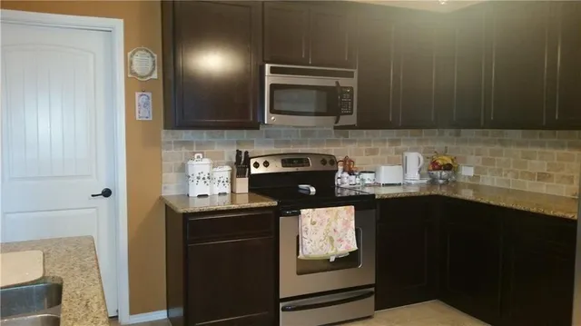 a kitchen with stainless steel appliances granite countertop a stove a sink and a microwave