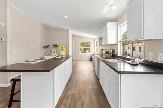 a kitchen with kitchen island granite countertop a sink a counter top space and stainless steel appliances