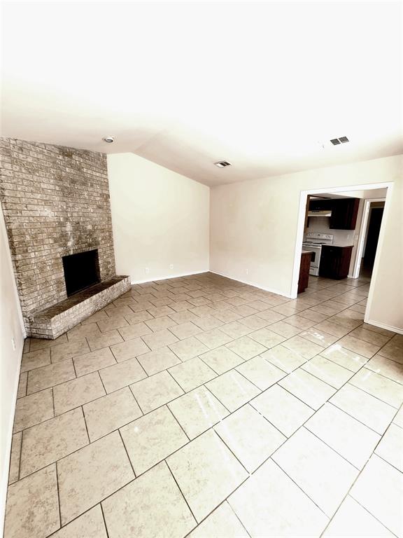 8811 Clearbrook Trail Austin, TX 78729 - Photo 11 of 38 lft A - A spacious living area features a brick fireplace and durable tile flooring, connecting seamlessly to the adjacent kitchen.