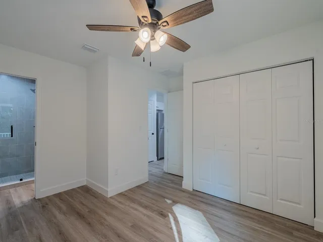 an empty room with wooden floor fan and windows