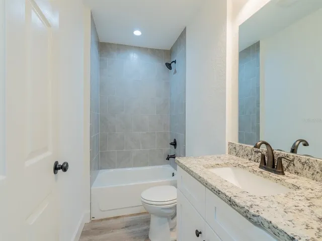 a bathroom with a granite countertop sink toilet and shower